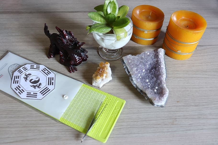Acupuncture needles on a table with gemstones and candles